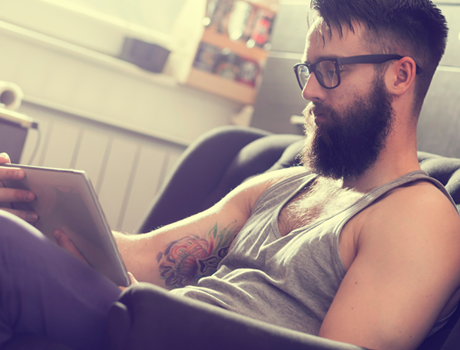a bearded tattooed man using a tablet