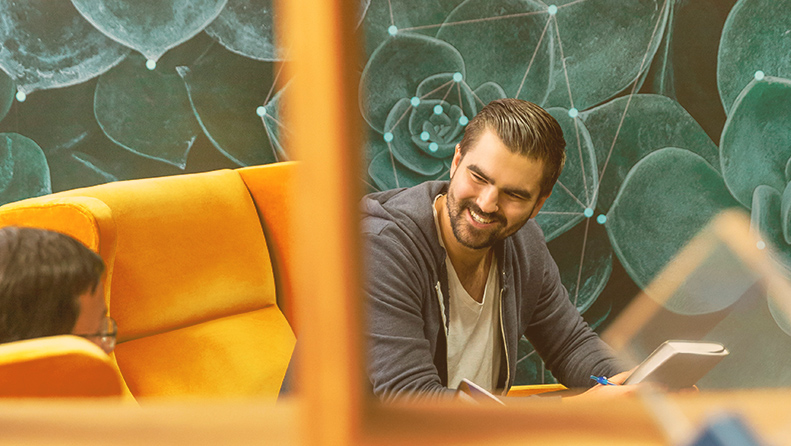 smiling man in an orange chair with a green background