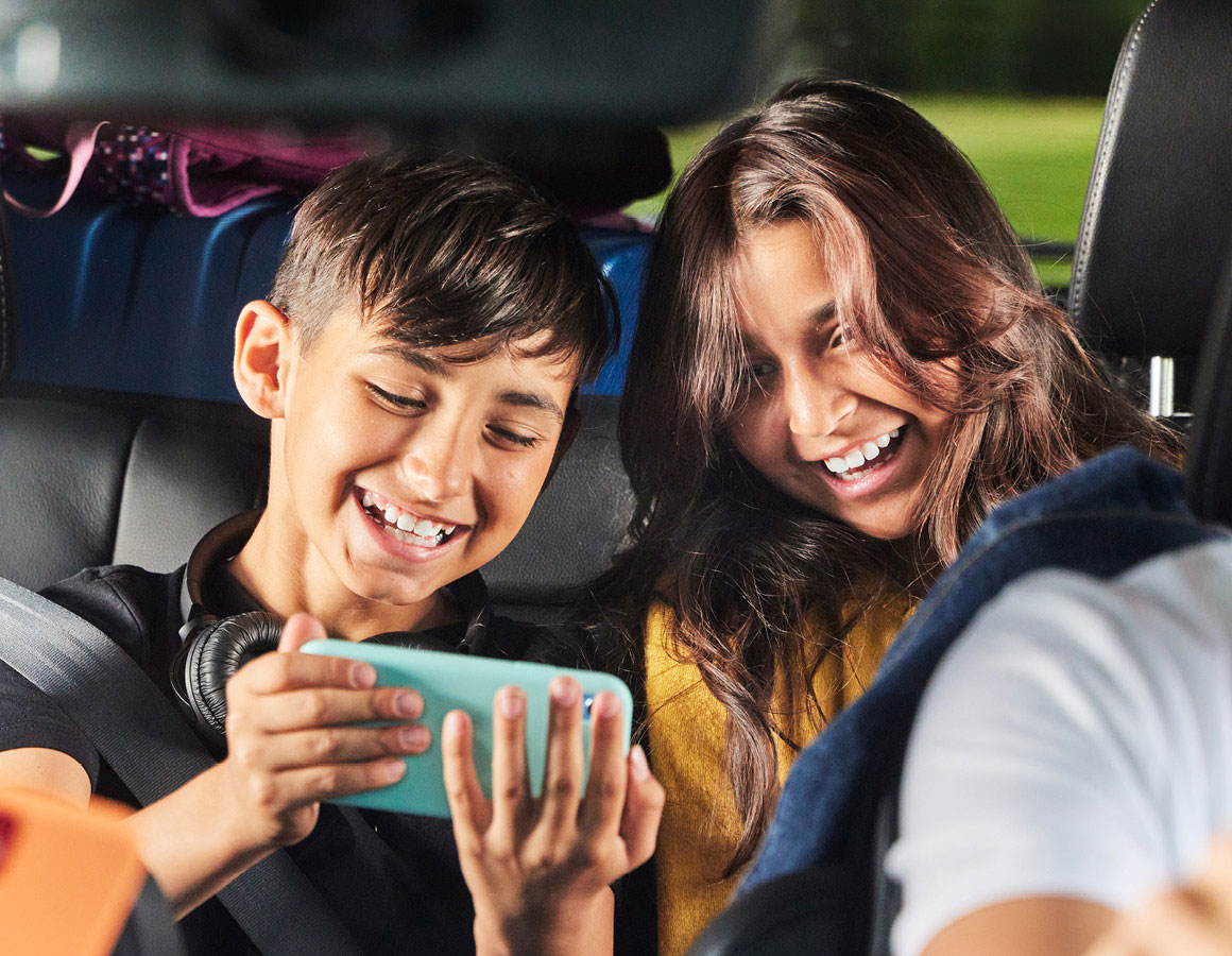 kids in a car watching something on their phone