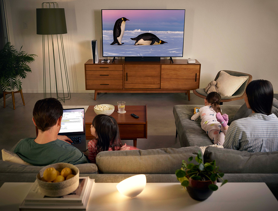 a family watching TV while also using a laptop and a tablet