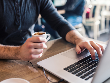 a man drinking an espresso and using a laptop