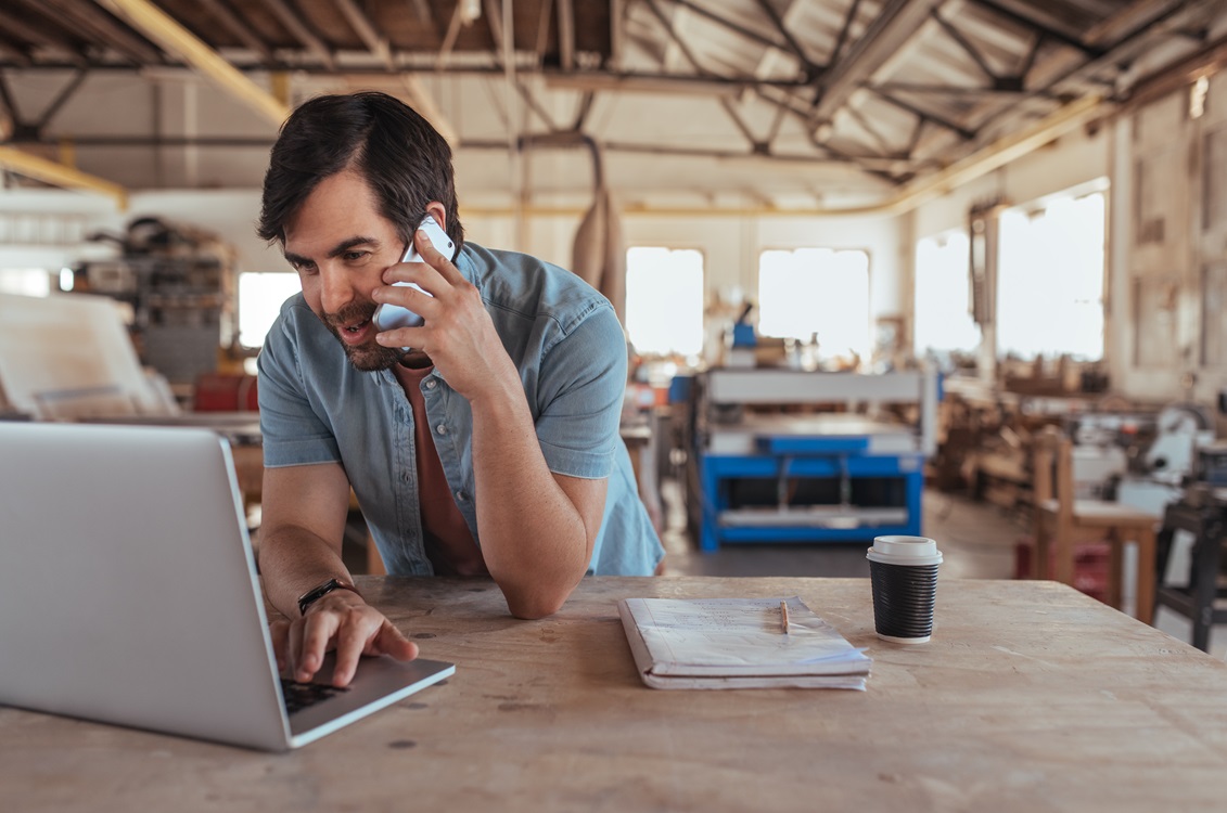 man on computer talking on cellphone