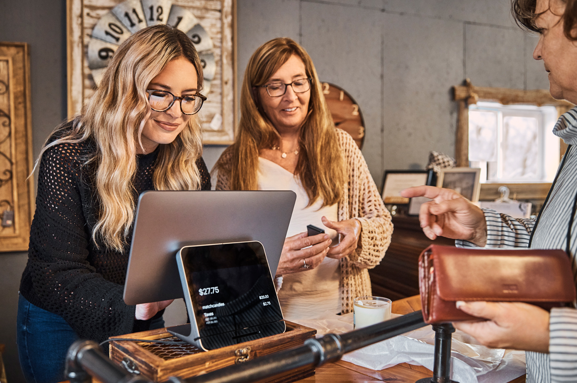 Computer and cell phone on table with a sign signifying Wi-Fi connectivity at this business