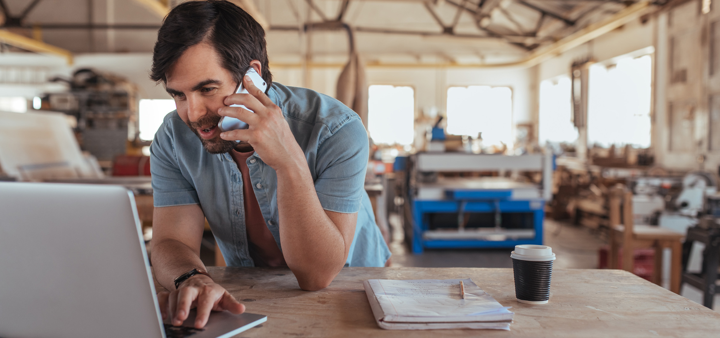 man at computer in warehouse on cellphone